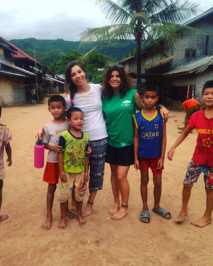 Two women posing with children in a village.