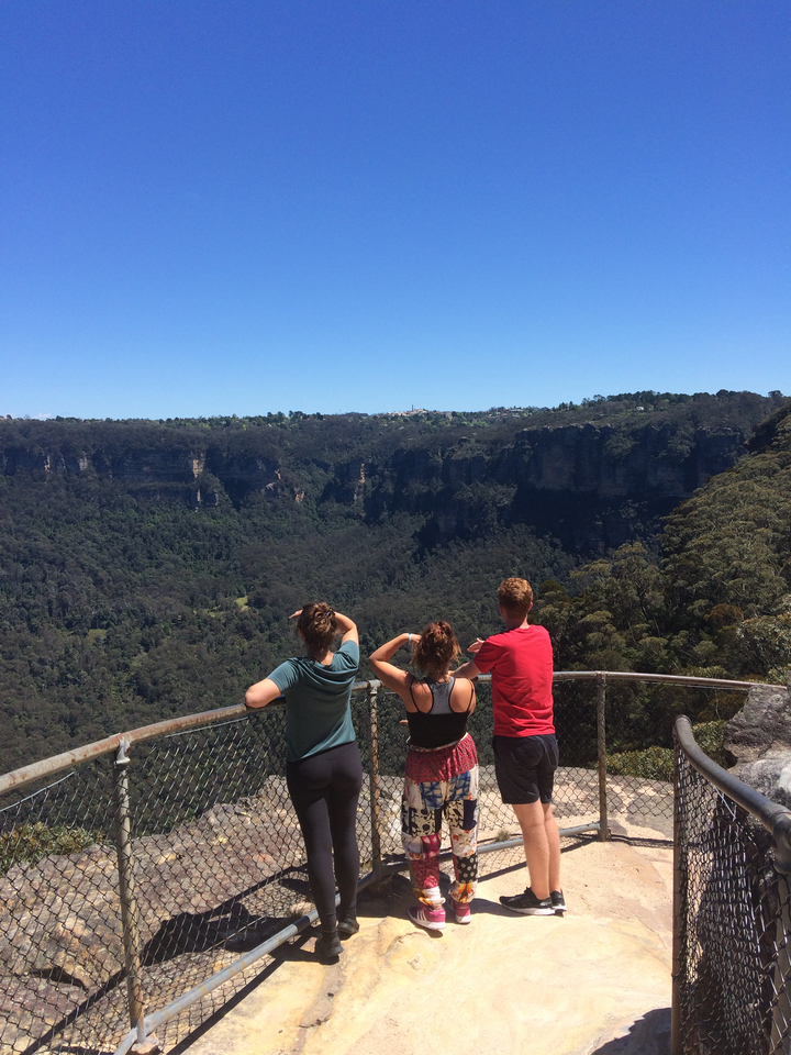 People overlooking a scenic valley from a viewpoint.