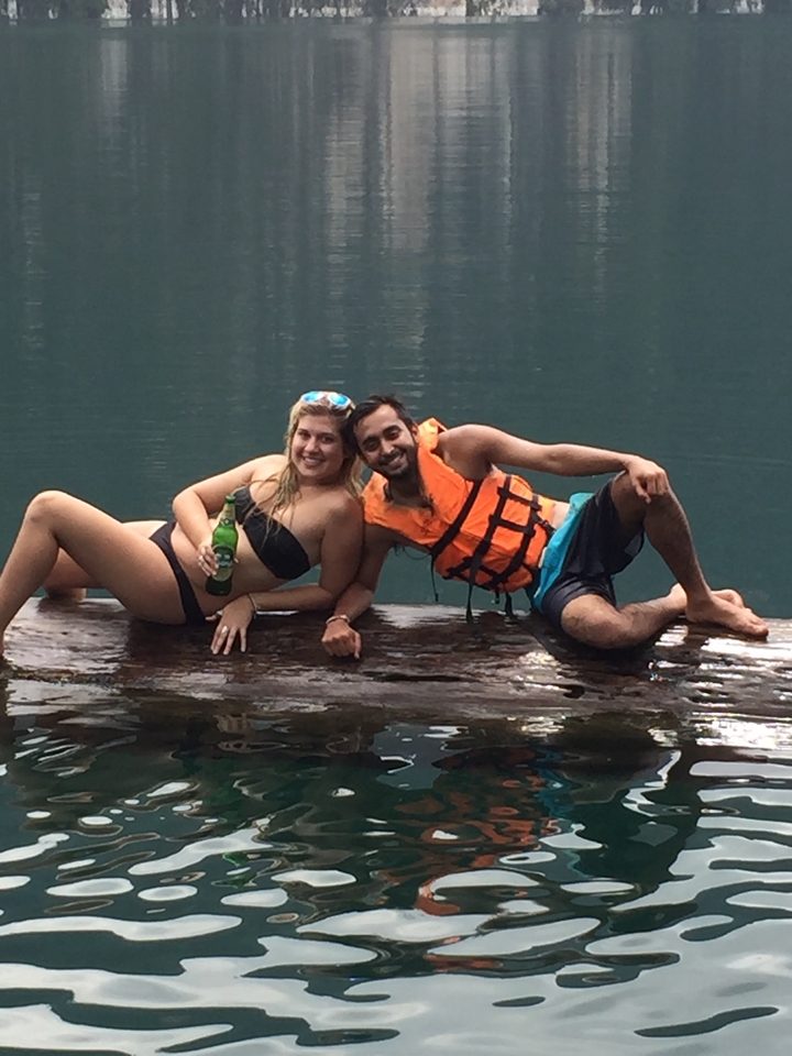 Two people reclining on a log floating in a lake.