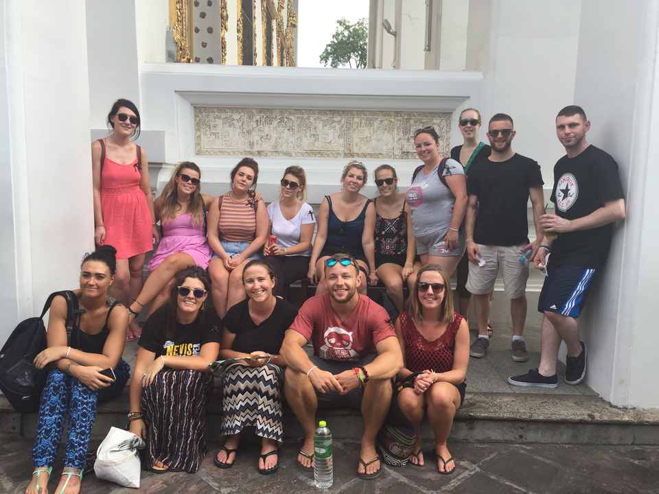 Groupe de personnes posant devant un mur historique.