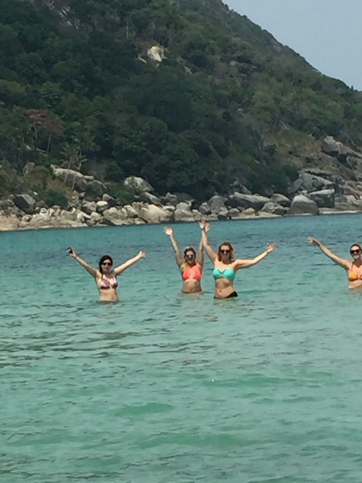 People enjoying swimming in the sea with rocky landscape.