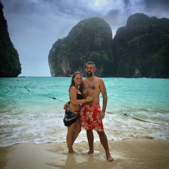 Couple posing on the beach with scenic cliffs in the background.