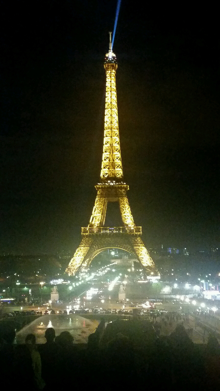 Illuminated Eiffel Tower at night in a city landscape.