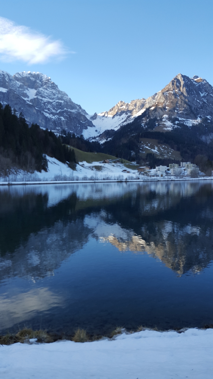 Snow-covered mountain landscape with buildings by a lake.