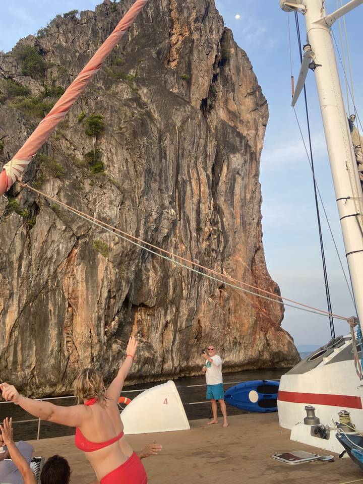 Des gens sur un bateau avec une falaise rocheuse en arrière-plan