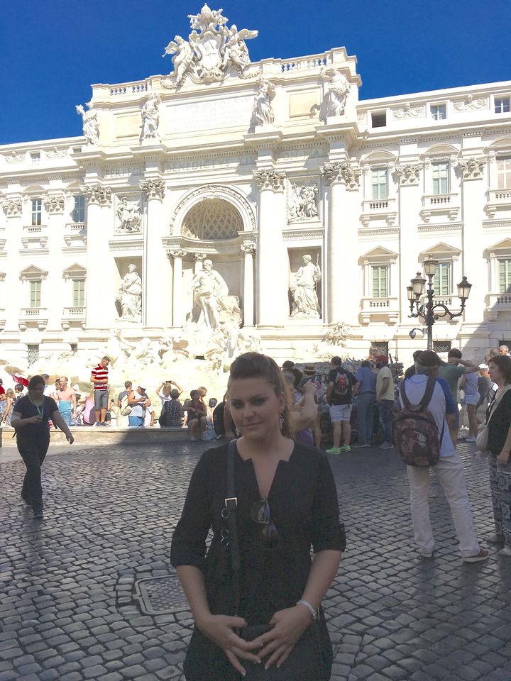 Person standing in front of the Trevi Fountain.
