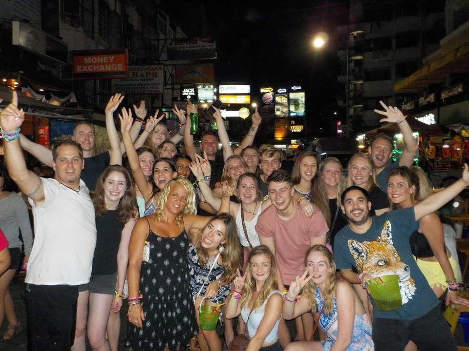 Large group enjoying a vibrant street at night with signs lit up.