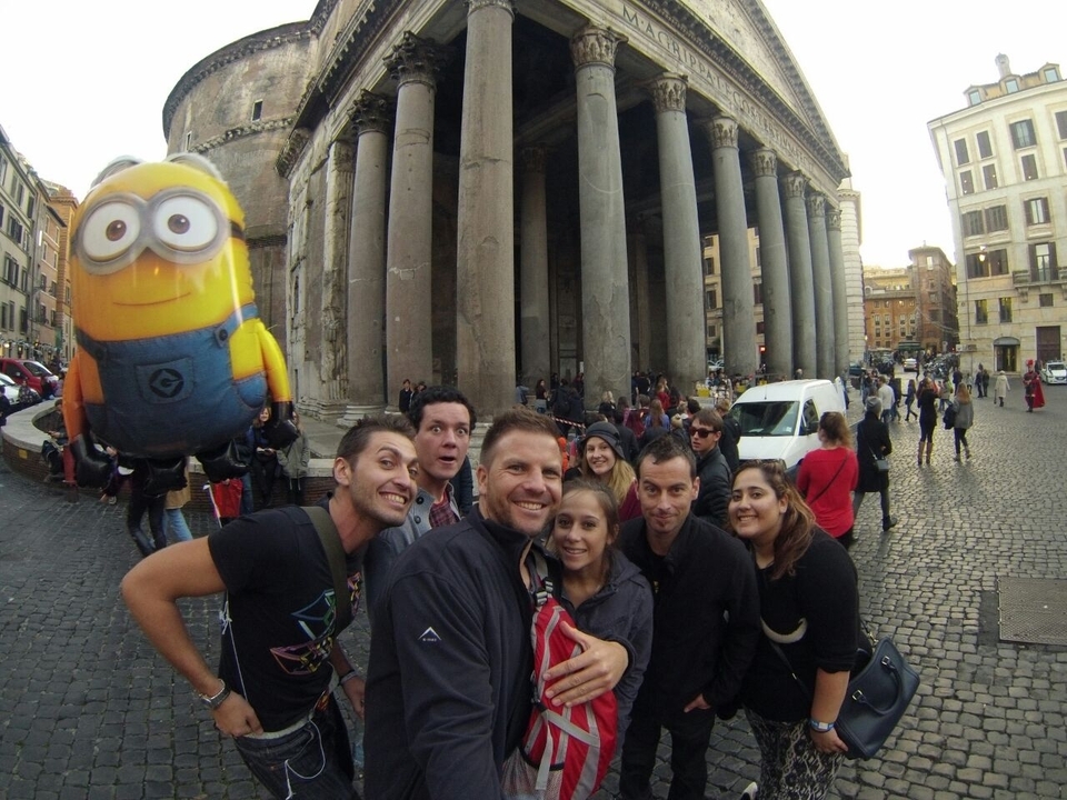 Group of people posing with a large minion balloon in a city square.