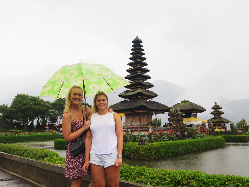 Two people holding an umbrella in front of a traditional temple.