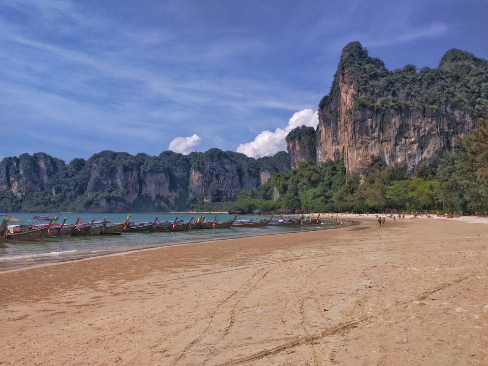 Beach with boats and cliffs in the background.
