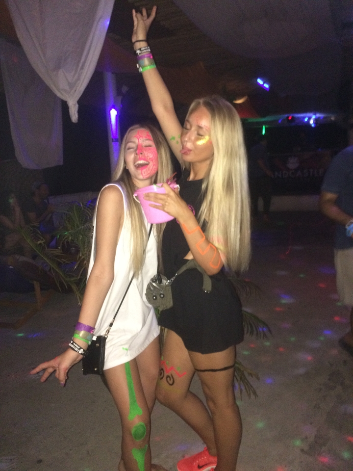 Two people posing indoors with neon paint on their faces.