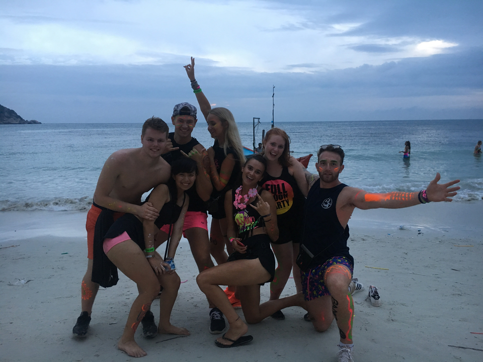Group of people posing on a beach with the ocean in the background.