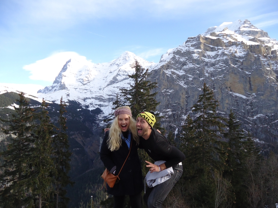 Two people posing with snowy mountains in the background.