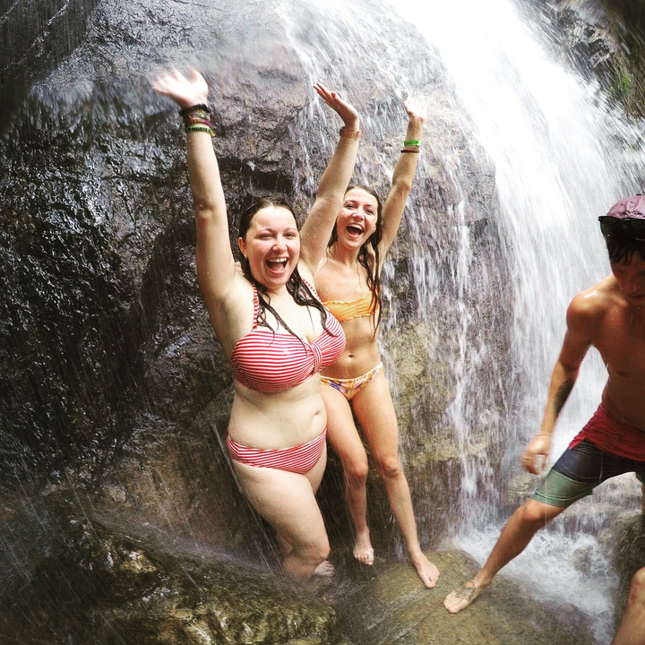 Two women enjoying a waterfall.