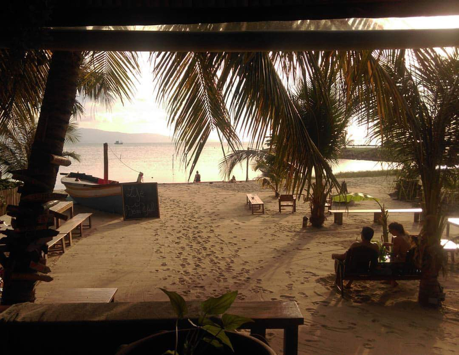 Beach scene with palm trees and a seated couple at sunset.