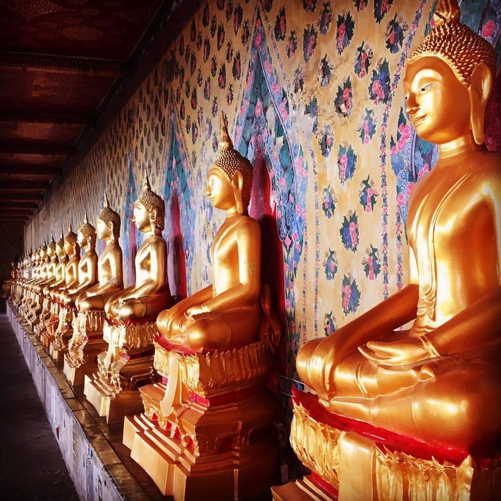 Row of golden Buddha statues in a temple setting.