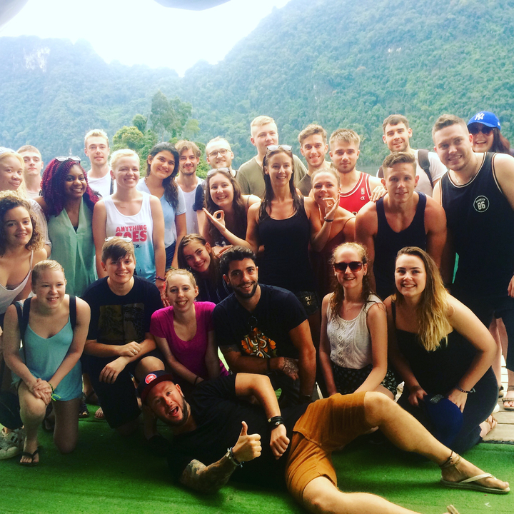 A group of people posing together with a scenic background of greenery and hills.