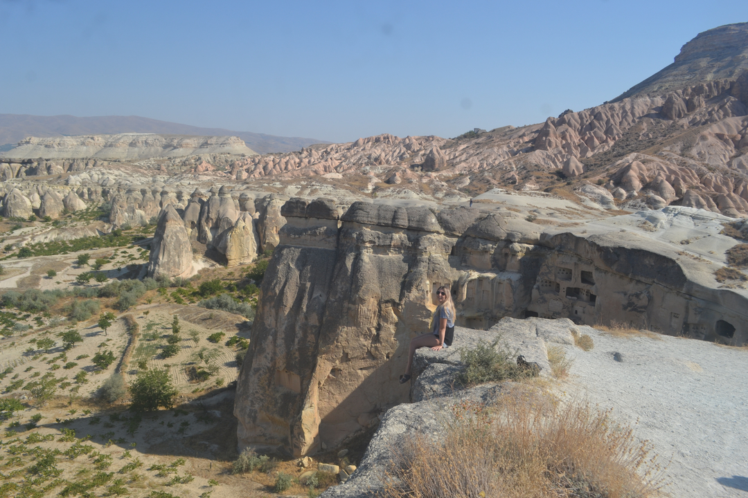 Personne assise sur une formation rocheuse surplombant un canyon pittoresque.