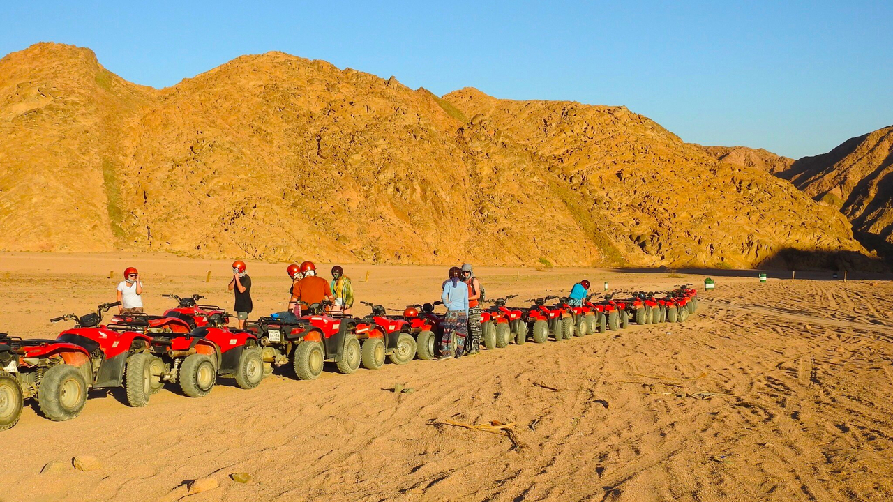 Group of people on quad bikes in the desert.