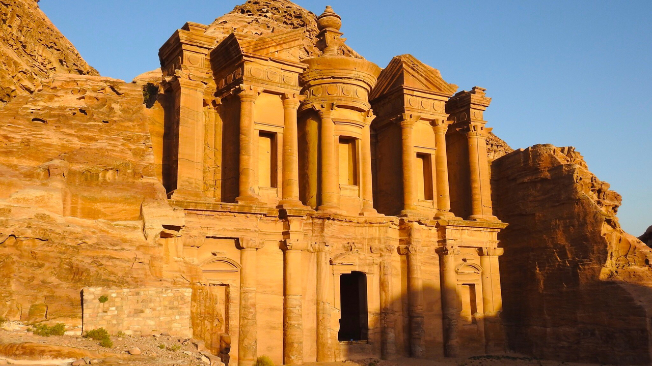 Monastery in Petra with cliff background.