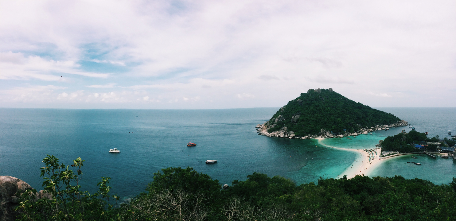 Aerial view of a small island with turquoise waters and boats.