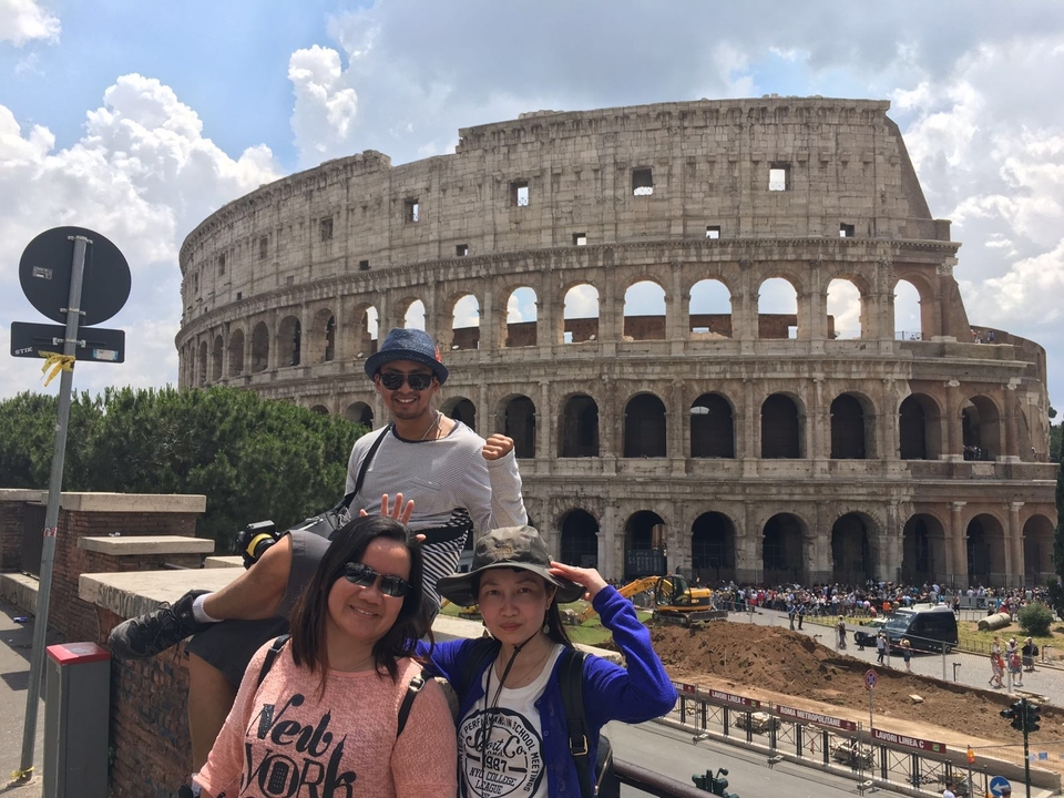 Tourists posing in front of the Colosseum.