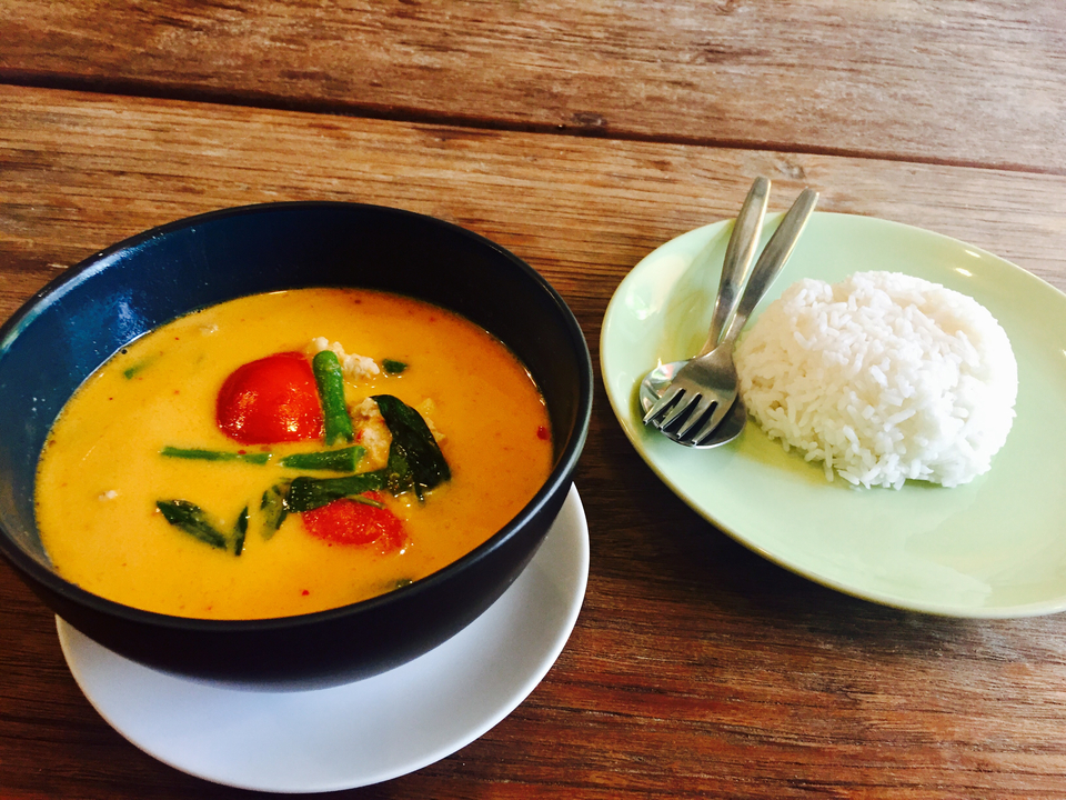 Bowl of curry with rice on a wooden table.