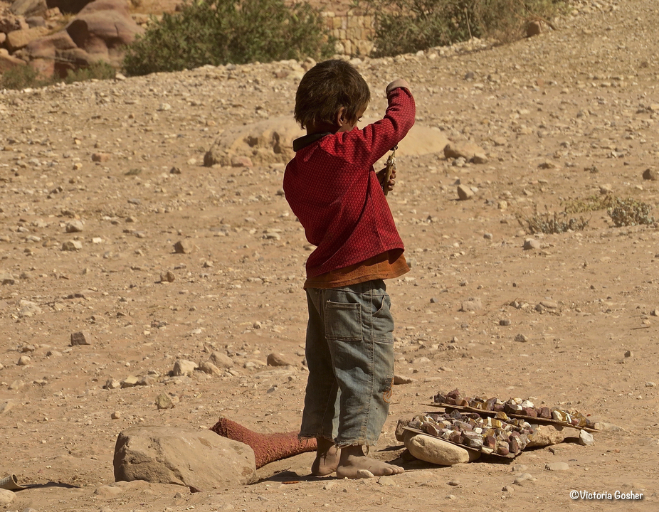 Child standing in a rocky, desert environment.