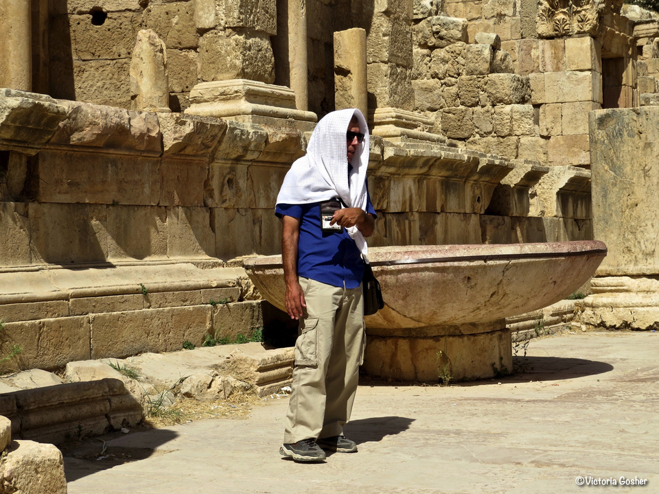 Person standing beside ancient stone architecture with a basin.