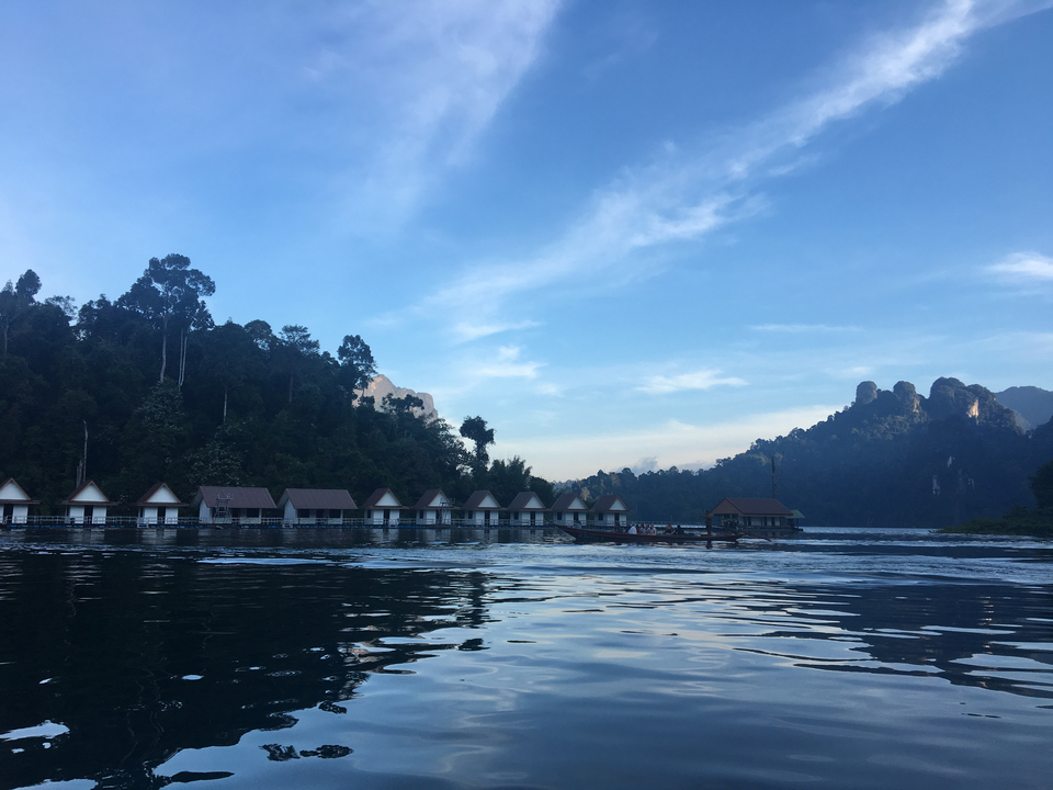 Floating houses on a lake with mountain backdrop.