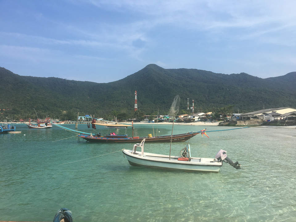 Boats docked in a serene bay with mountains.