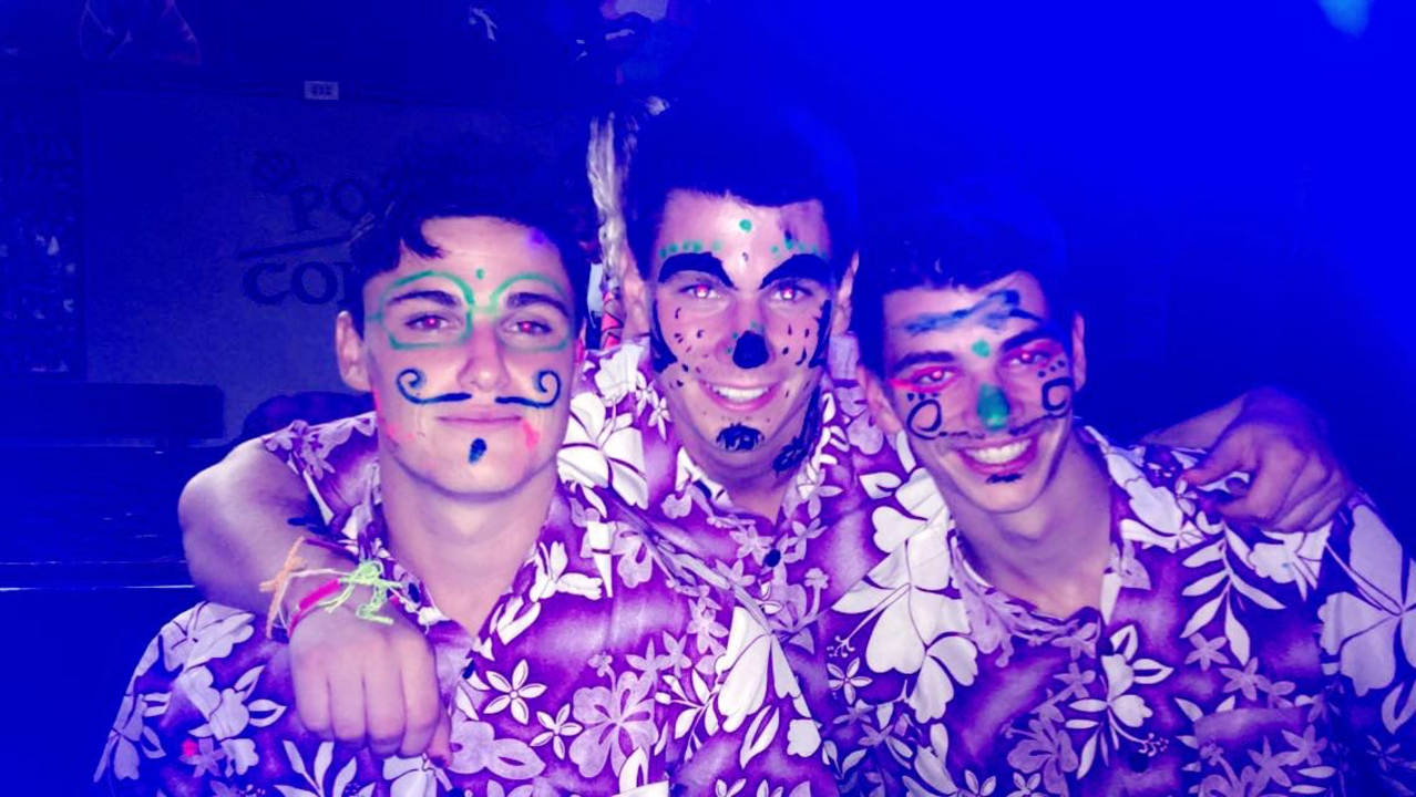 Three men with neon face paint in a club