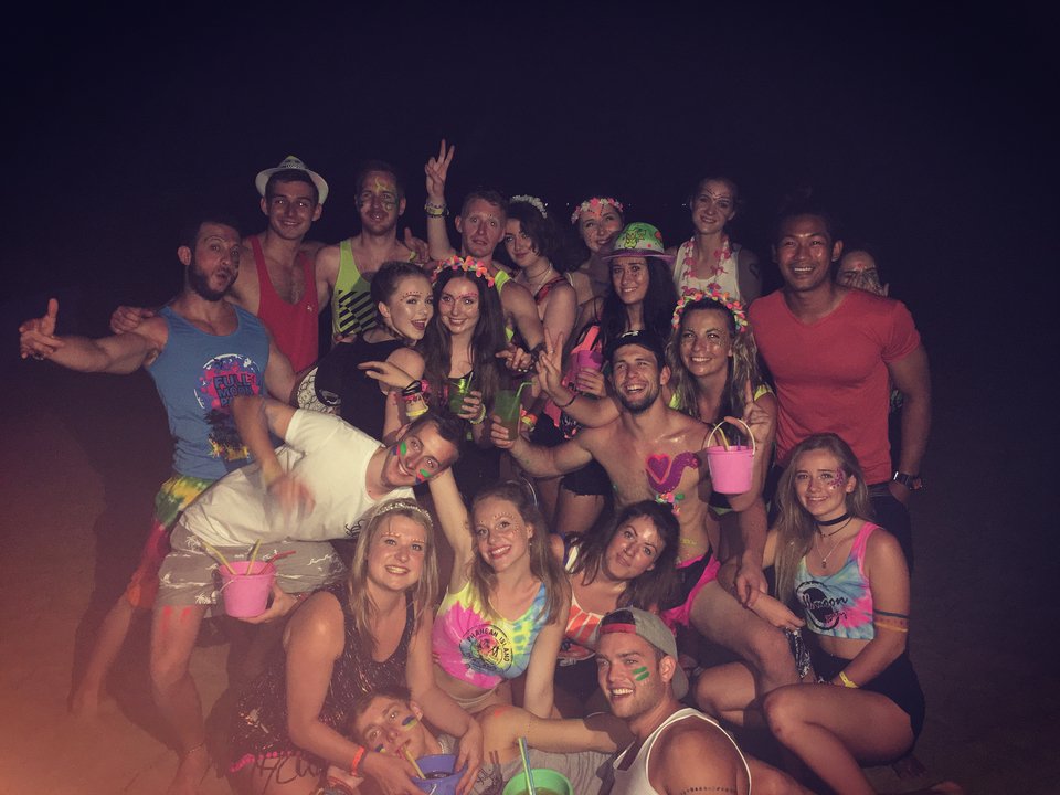 Group of people with neon body paint posing at night.