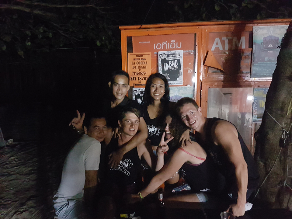 Group of people posing in front of an ATM at night.