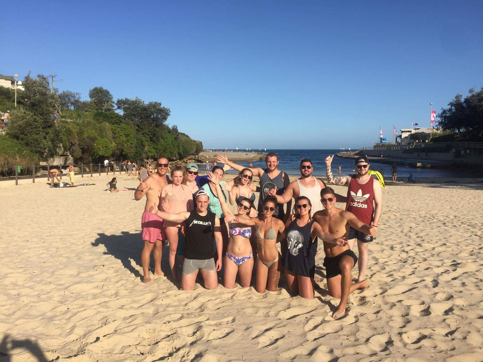Group of friends posing on a sandy beach with ocean view.
