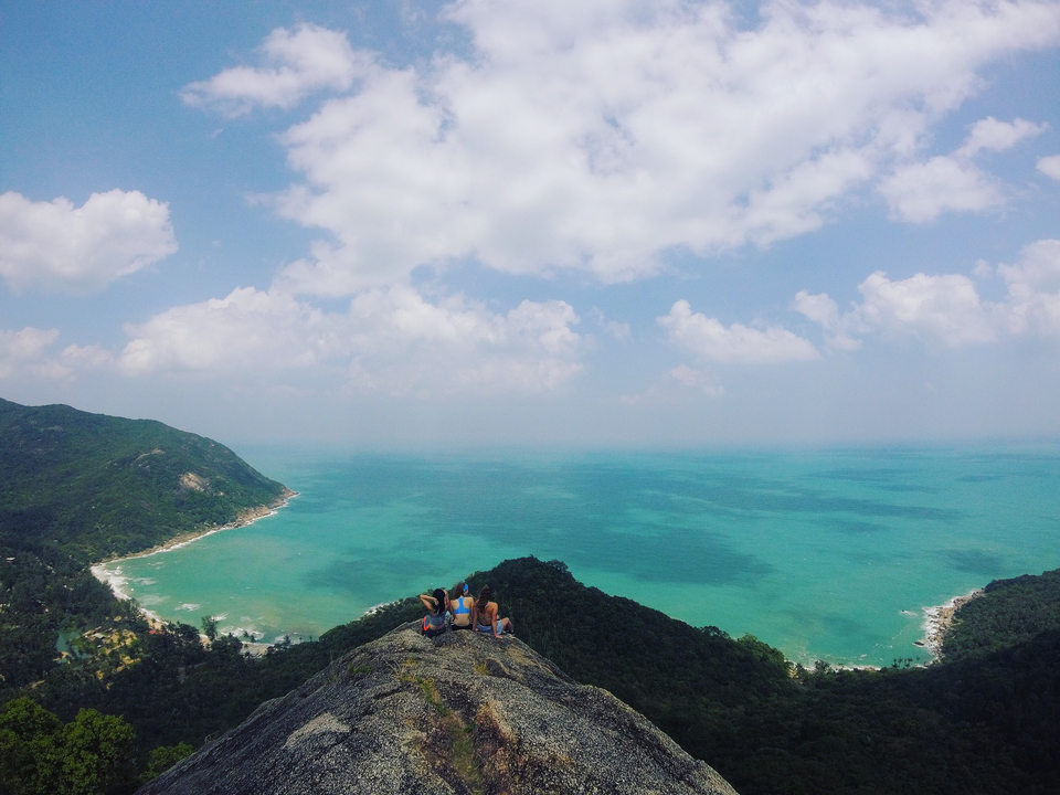 Panoramic view of a vast ocean with cliffs and people at the top.