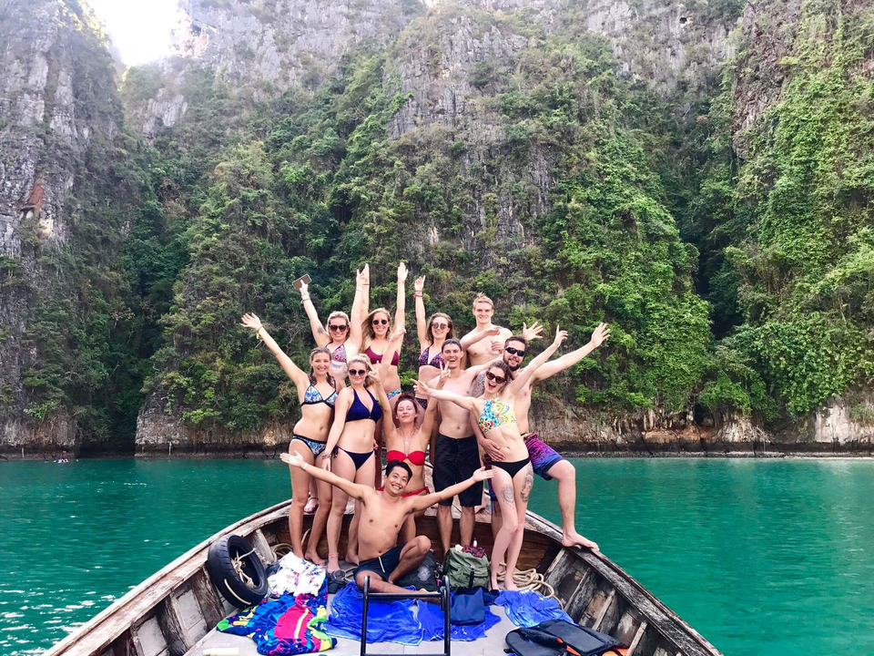 People on a boat with lime cliffs covered in greenery.