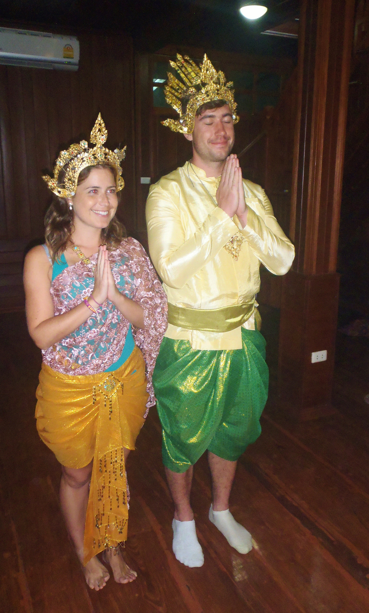 Two people in traditional attire posing with a greeting gesture.