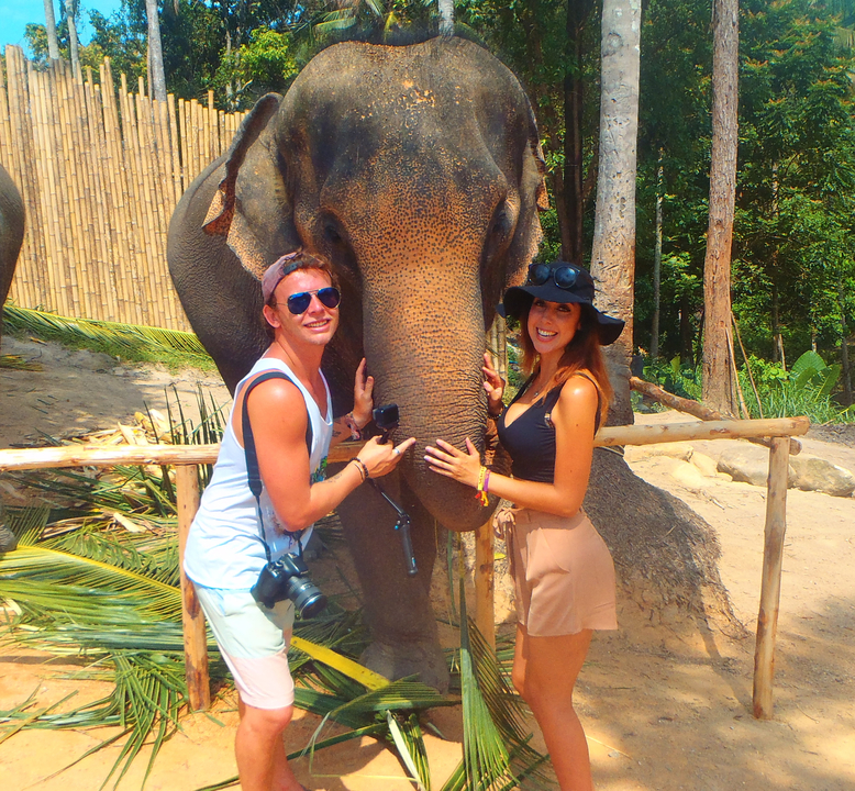 Two people posing with an elephant.
