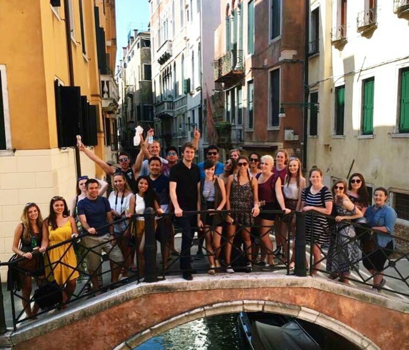 Group of people posing in a narrow street with colorful buildings.