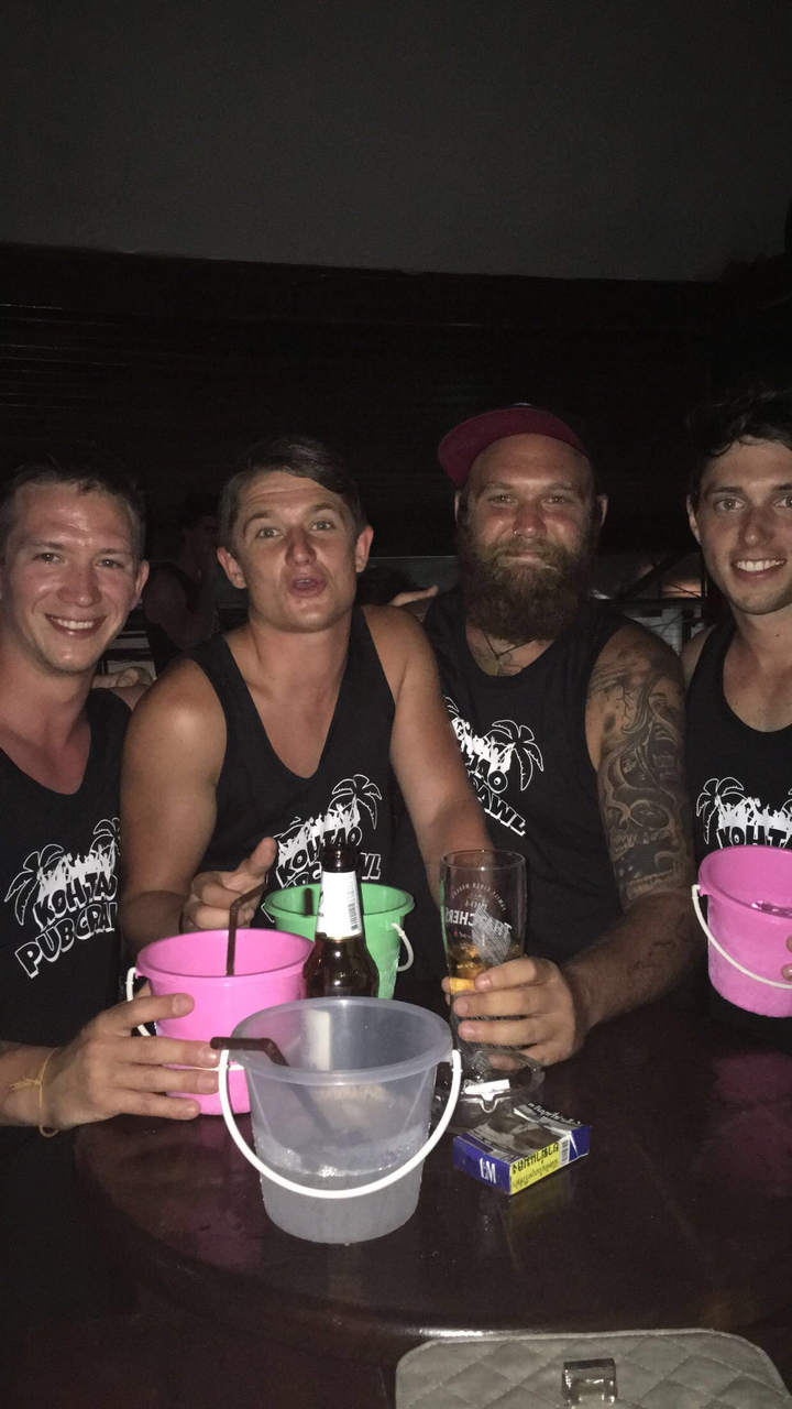Group of men in matching tank tops at a bar.