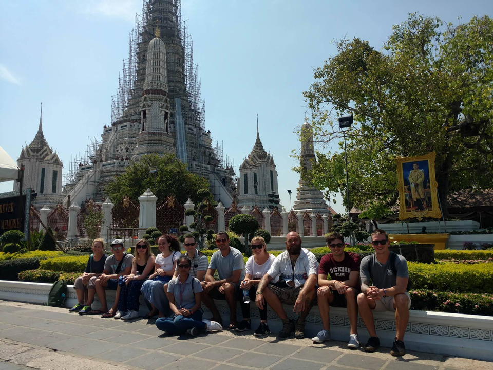 Group of people sitting in front of a large temple.