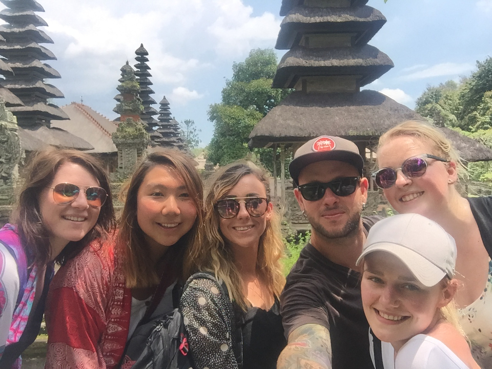 Group of people posing in front of traditional Bali architecture.
