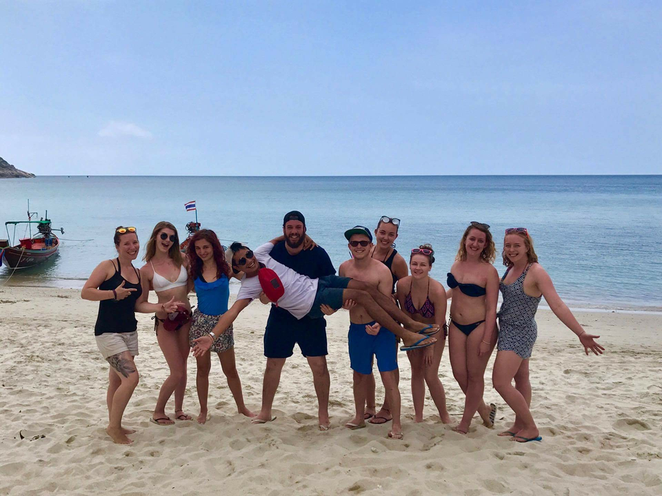 Group of people posing on a beach.