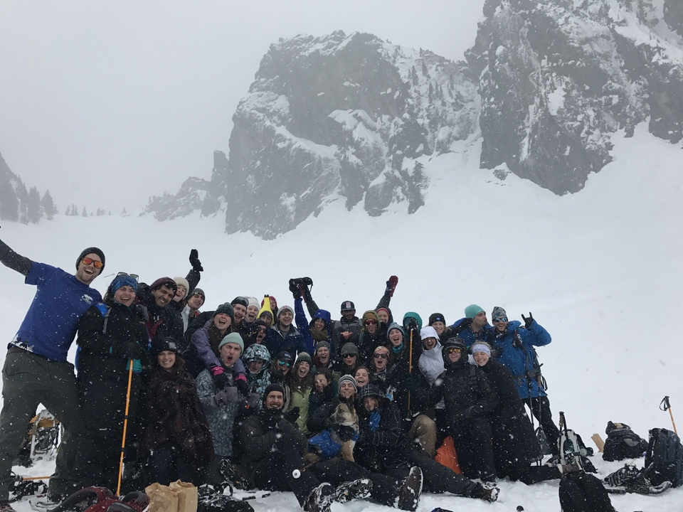 Group of people posing in snow in front of a rocky mountain