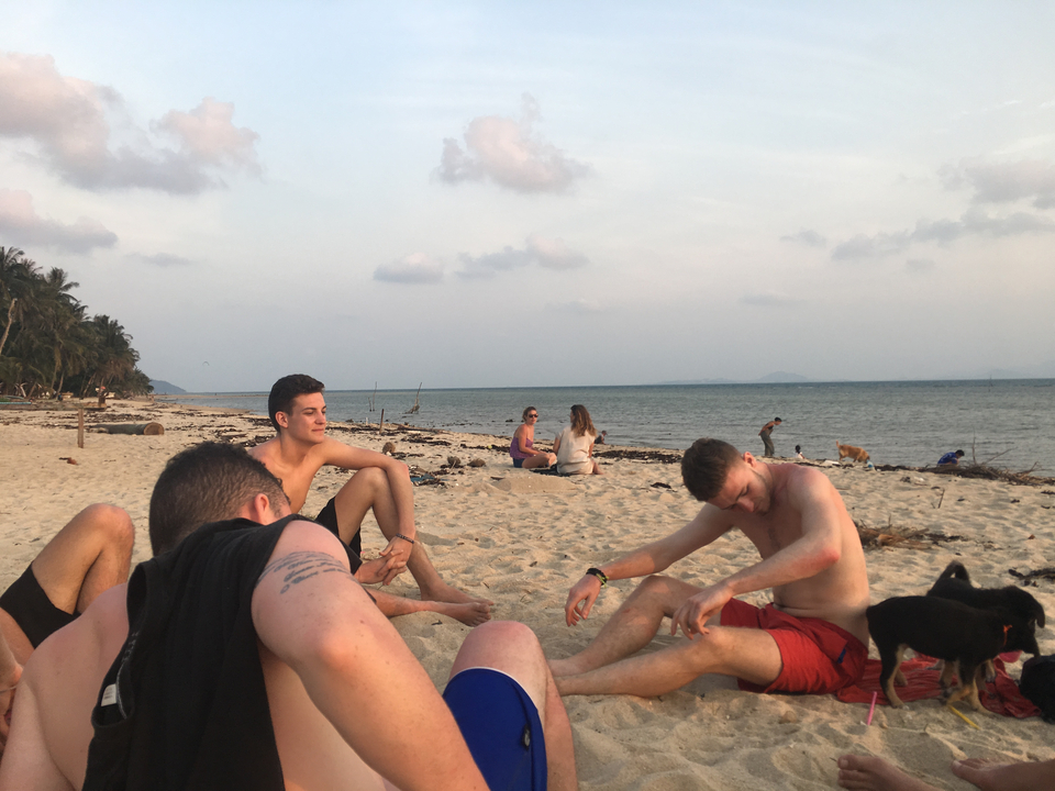People sitting on a beach at sunset.