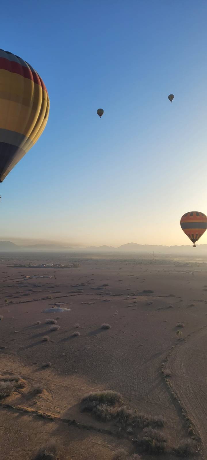 Hot air balloons in the sky over a desert landscape.
