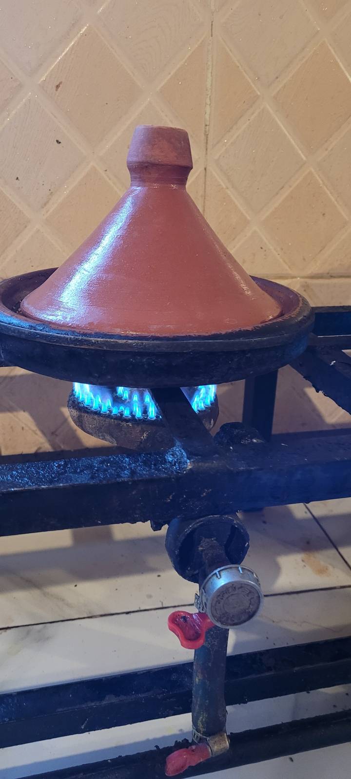 Tajine pot on a stove with blue flame.