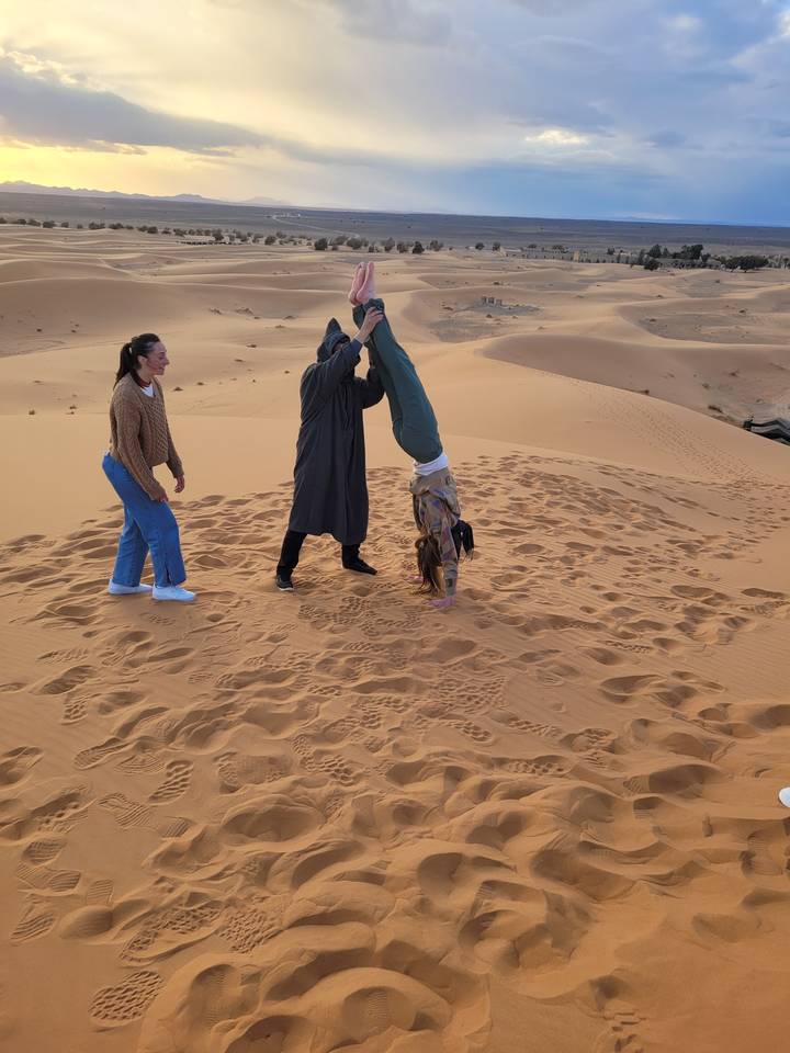 People walking on sand dunes during sunset.