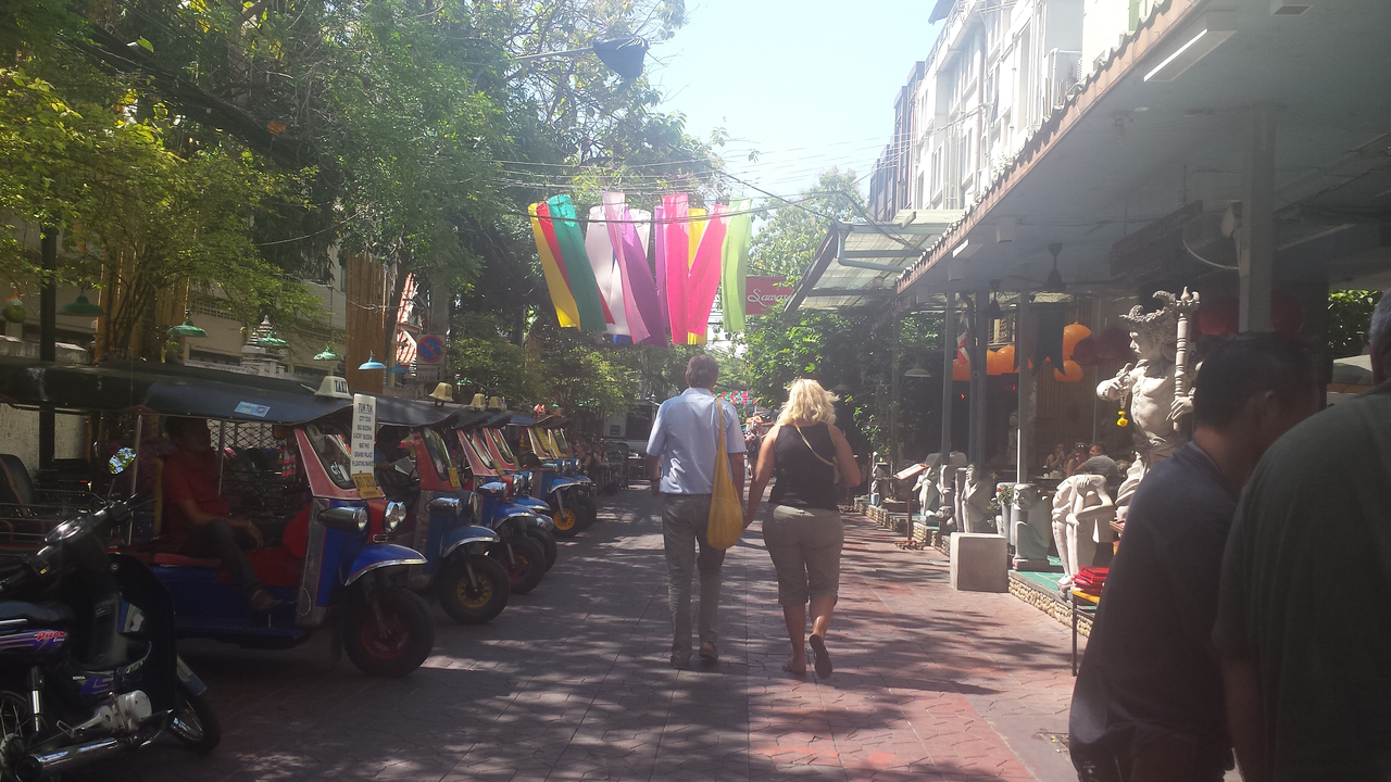 Tourist street with tuk-tuks and colorful decorations.